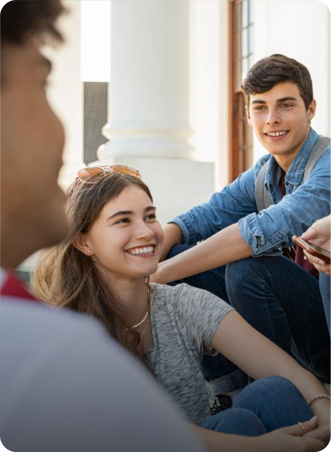 Smiling college students sitting on campus steps and chatting