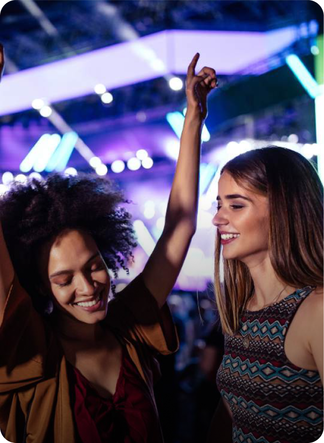 Two women dancing and smiling at a lively nightclub or event