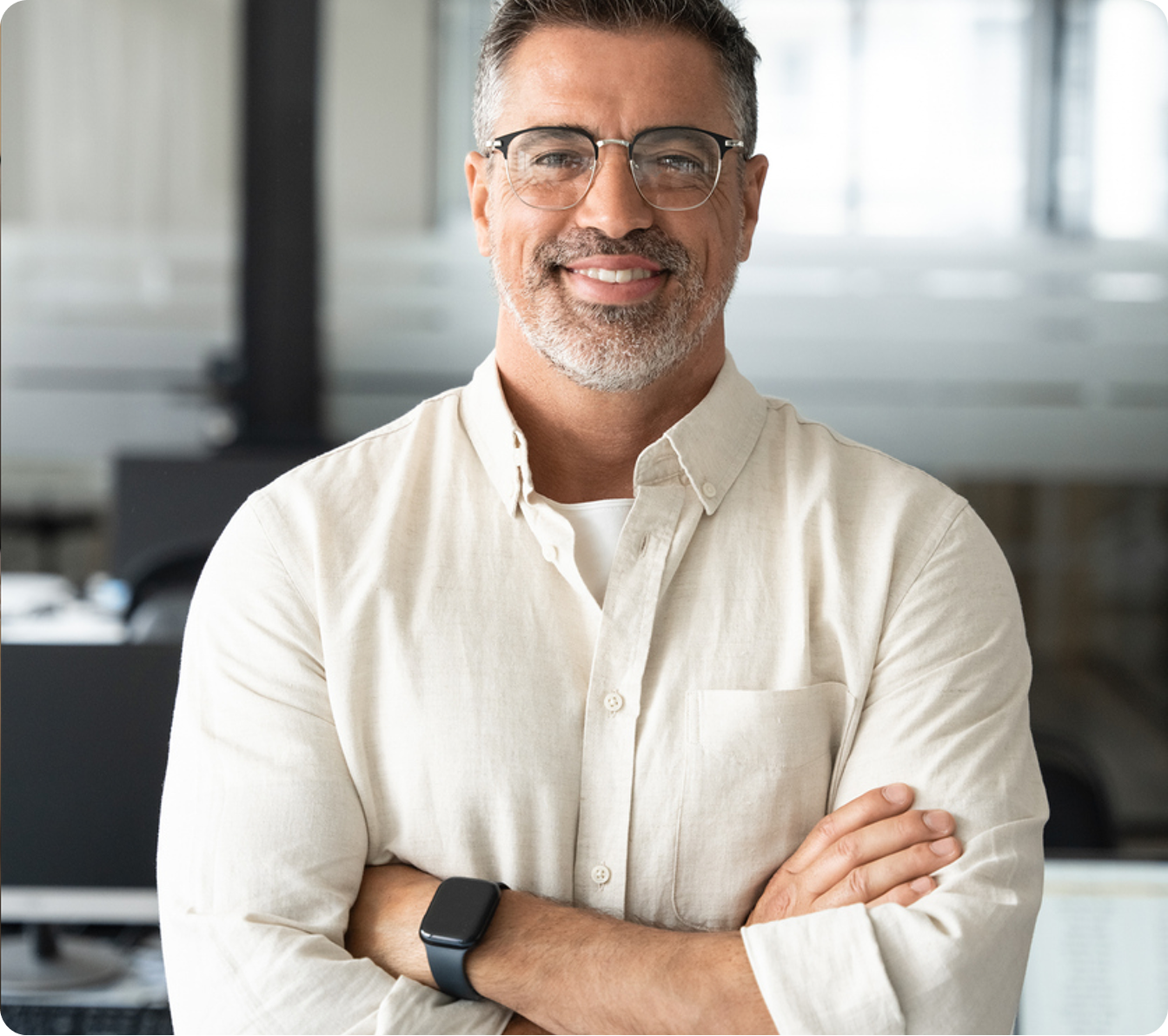 Middle‑aged man with glasses smiling in an office, arms crossed
