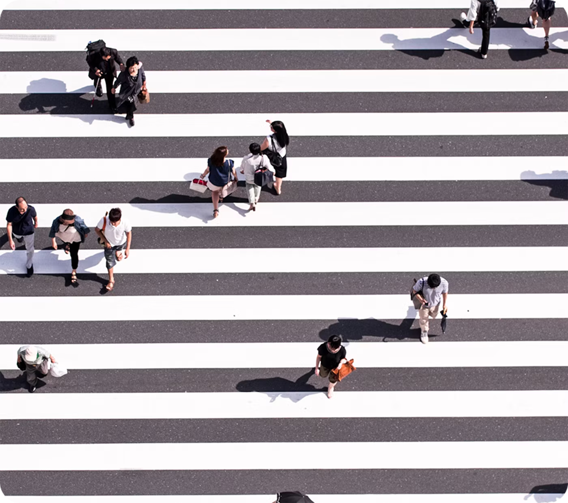 Aerial view of pedestrians walking across a black-and-white striped crosswalk